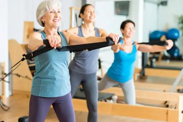 Toning Arms After 60: Empowering Womens Fitness Through Effective Weight Training 2 older woman doing weight training Bedford and resistance in the gym to tone upper arms