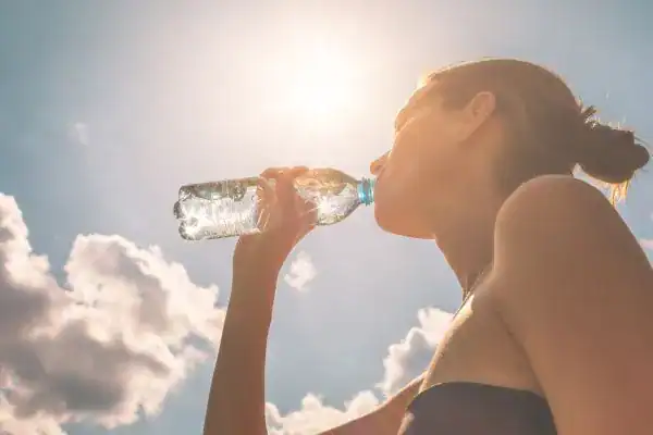 Hydration: The Secret Ingredient for a Toned Stomach and Enhanced Fitness 3 Image of woman drinking water to hydrate Bedford after run.