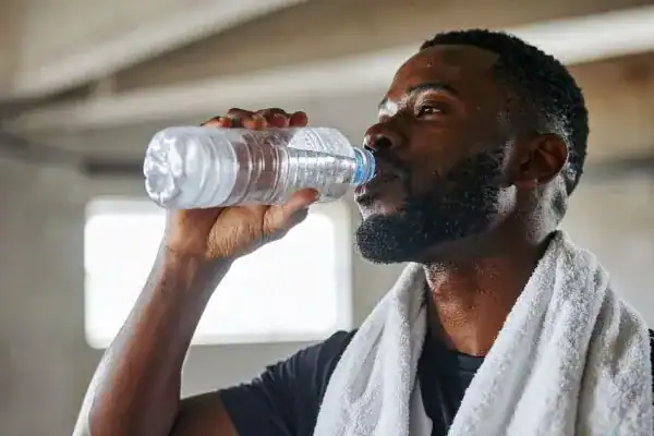 Image of man drinking water to improve hydration Bedford after work out.